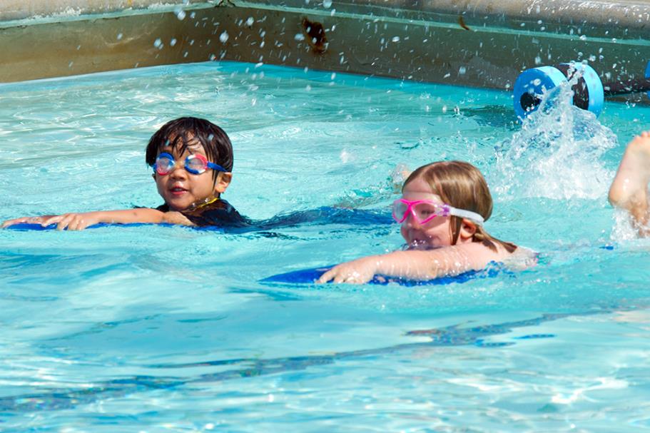 Two female swimmers learning to kick with kickboards