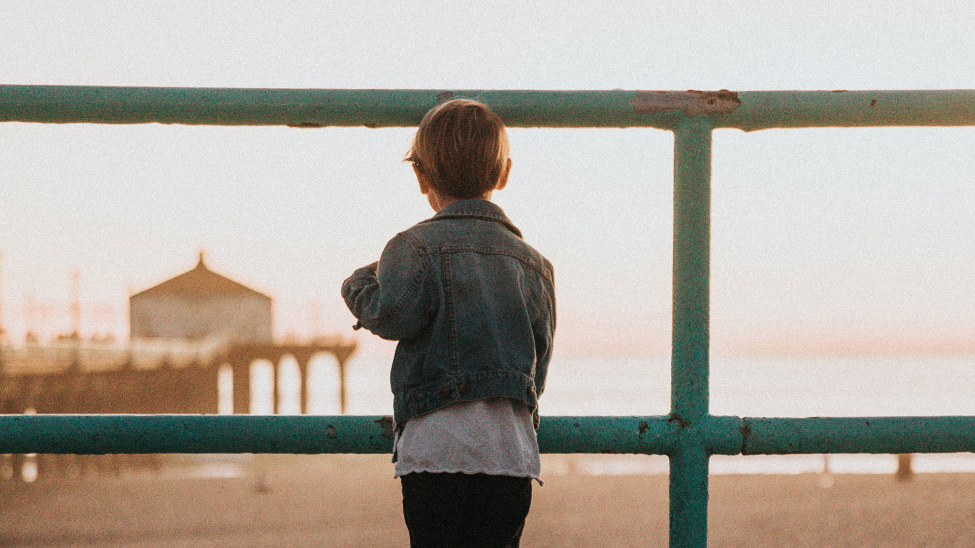 Child at railing looking at Manhattan Beach Pier Photo by Nathan Dumlao